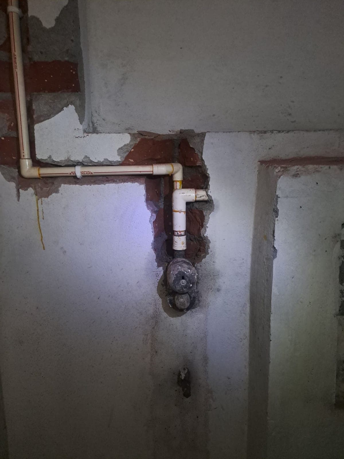 Completed basement plumbing work with white PVC pipes and an exposed valve area